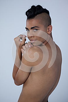 Sensuous transgender looking over shoulder while standing against gray background