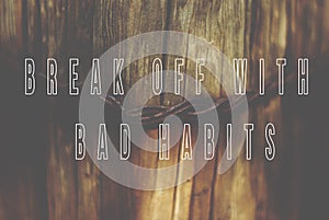 Sentence break off with bad habits written on natural wooden background with metal wire in a middle.