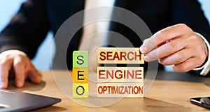 SEO concept, man stacks wooden blocks with the words Search Engine Optimization.