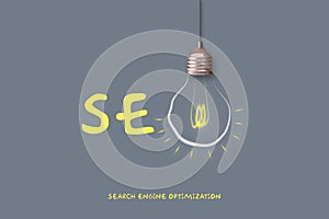 SEO concept. Search engine optimization. Glowing light bulb and word on a gray background