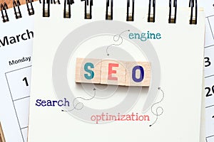 SEO Search Engine Optimization abbreviation composed of wooden letters located on an office notebook