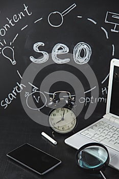 SEO Search engine optimization concept Magnifying glass, clock, smartphone on a black background with an inscription
