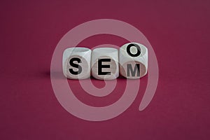 SEO versus SEM. Turned a cube and changed the expression SEO to SEM or vice versa. Concept for Search Engine Optimization and