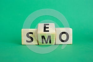 SEO vs SMO symbol. Wooden cubes with words SMO and SEO. Beautiful green background. SEO vs SMO and business concept. Copy space photo