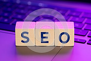 SEO word on wooden blocks on laptop with colorful lights