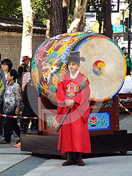 A man in front of a large drum at the Changing of the Royal Guard ceremony at the main entrance to Deoksugung Palace in Seoul