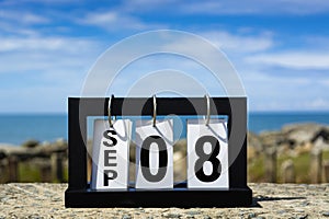 Sep 08 calendar date text on wooden frame with blurred background of ocean.