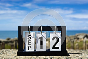 Sep 12 calendar date text on wooden frame with blurred background of ocean.