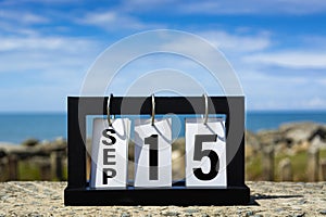 Sep 15 calendar date text on wooden frame with blurred background of ocean.