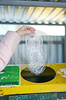 Separate garbage collection. The girl throws plastic bottles in a container for recycling plastic