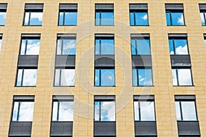 Separate windows office building yellow wall with clouds sky mirror