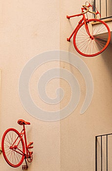 The separated front and rear half of a vintage red bicycle pinned to the wall of a minimalist building block