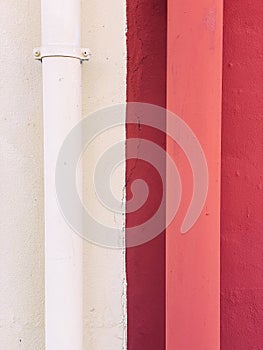 Separation of two houses. One white side, one red. Two drains in different colours