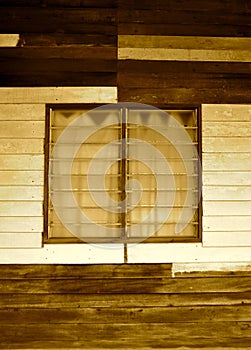 Sepia image of louvred windows in a basic wooden dwelling