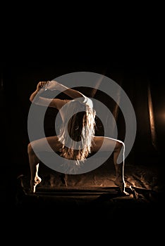Sepia photography silhuette of beautiful woman in dancing pose on dark background.