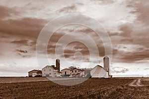 Sepia picture of an old-fashioned Amish farm house with 2 silos in rural Pennsylvania, Lancaster County, PA, USA