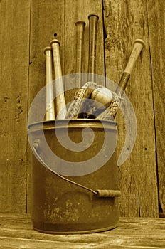 (Sepia) Vintage baseball wood bat, glove, and ball in pail