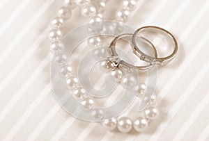 Sepia vintage retro style wedding and diamond engagement rings with pearl necklace