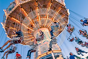 Sept. 2, 2012 - Vancouver, BC: Fun fair riders on whirling retro swing ride, late afternoon at PNE Exhibition.