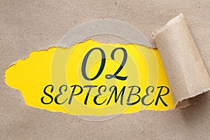 september 02. 02th day of the month, calendar date.Hole in paper with edges torn off. Yellow background is visible