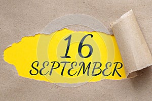 september 16. 16th day of the month, calendar date.Hole in paper with edges torn off. Yellow background is visible