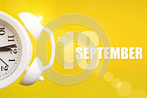 September 18th. Day 18 of month, Calendar date. White alarm clock on yellow background with calendar day. Autumn month, day of the