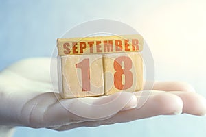 september 18th. Day 18 of month,Handmade wood cube with date month and day on female palm autumn month, day of the year concept