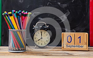 September 1st date, alarm clock and colorful pencils on blackboard background