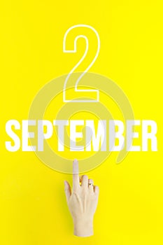 September 2nd. Day 2 of month, Calendar date.Hand finger pointing at a calendar date on yellow background.Autumn month, day of the