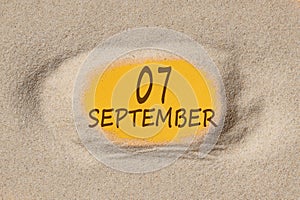 September 7. 7th day of the month, calendar date. Hole in sand. Yellow background is visible through hole