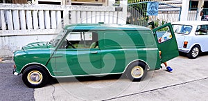 September 29, 2018: Green and Blue/white classic Mini cooper van parked on the street and in front of house