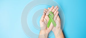 September World lymphoma and October Mental health day Awareness month, Woman holding lime green Ribbon color on blue background