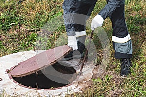 On a septic sewer well, a worker opens the manhole cover. Plumbing work