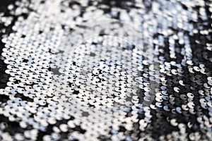 Sequin fabric texture. Shiny silver sparkling background. Clothing piece of glitter metallic for a glamorous party