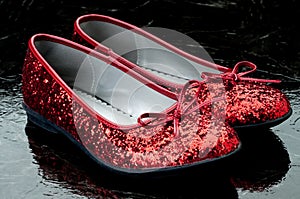 Sequined red slippers on dark tile.