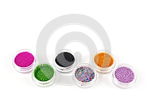 Sequins for nails of different colors in an assortment in boxes on a white background
