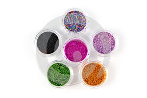 Sequins for nails of different colors in an assortment in boxes on a white background