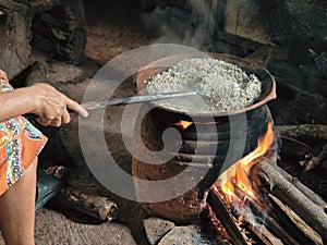 Serang woman is roasting rice in a hut with firewood