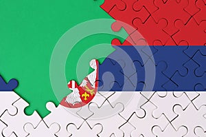 Serbia flag is depicted on a completed jigsaw puzzle with free green copy space on the left side