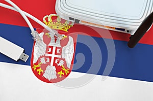Serbia flag depicted on table with internet rj45 cable, wireless usb wifi adapter and router. Internet connection concept