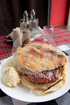 Serbian burger served in home made bun - Leskovacka pljeskavica u lepinji photo