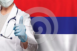 Serbian doctor's hand showing thumb up positive gesture on flag of Serbia background
