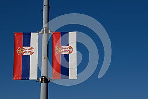 Serbian flags against the blue sky on a sunny day in the center of Belgrade. Red blue white tricolor with the symbol of