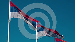 Serbian flags flutter in the wind against the blue sky on a sunny day in the center of Belgrade. Red blue white tricolor