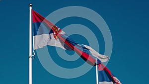 Serbian flags flutter in the wind against the blue sky on a sunny day in the center of Belgrade. Red blue white tricolor