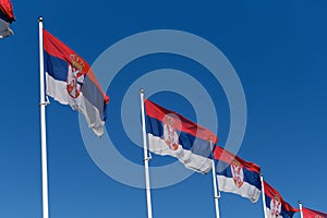 Serbian flags flutter in the wind against the blue sky on a sunny day in the center of Belgrade. Red blue white tricolor