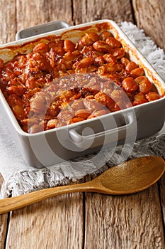 Serbian food: prebranac baked beans with onion close-up in baking dish. vertical