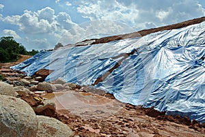 The plastic sheet is spread over the surface of the slope to prevent erosion. photo