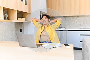 Serene African-American woman using laptop for remote work or studying, sitting at the table and resting, holding hands