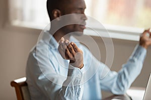 Serene african guy sitting indoors relaxing meditating